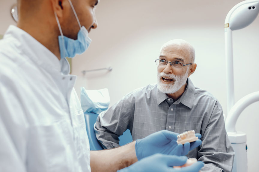 Elderly Patient Discussing Dental Bridge With Dentist