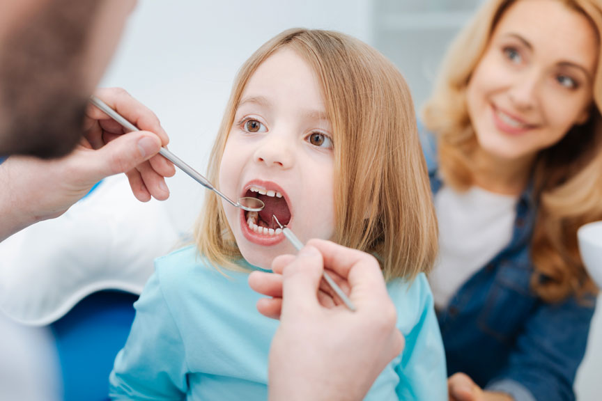 Pediatric Dentist in Houston Examines a Child's Teeth Using a Dental Explorer & Mirror
