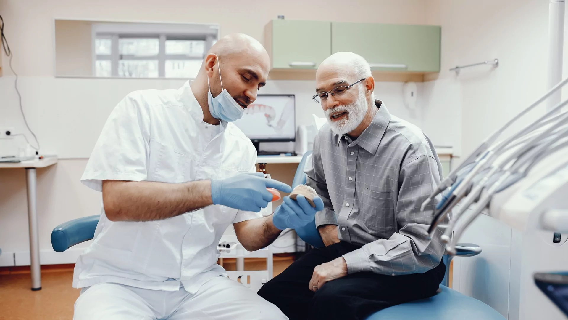 A Dentist Explaining Teeth Model To Patient