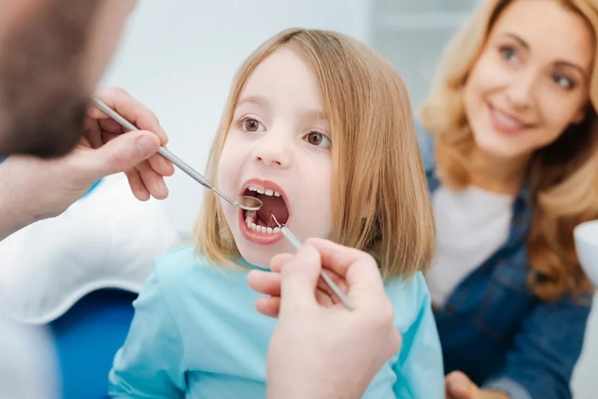 Pediatric Dentist Examines a Child's Teeth Using a Dental Explorer & Mirror
