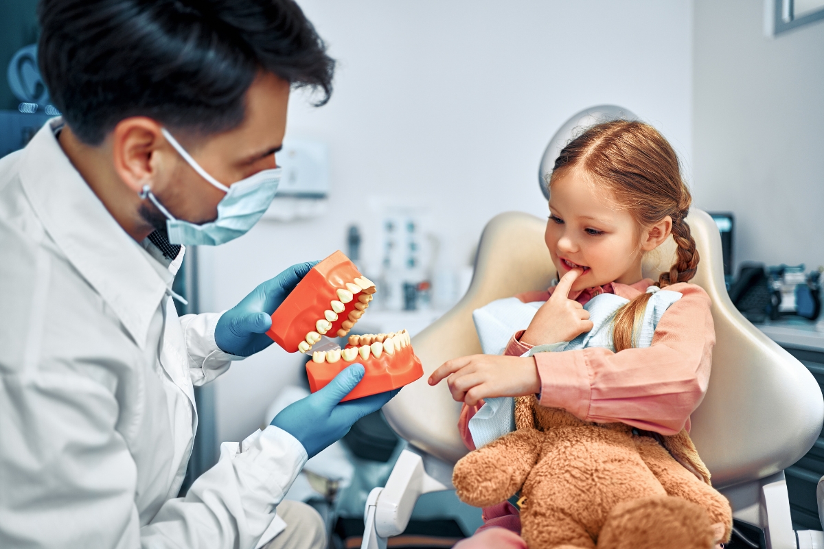 Child learning dental hygiene from pediatric dentist during checkup visit
